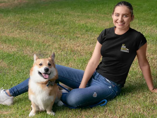 AZ Dog Boss trainer relaxing on the grass with a corgi